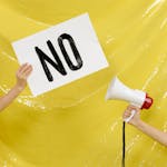 Conceptual protest image with a placard and megaphone against a yellow backdrop.